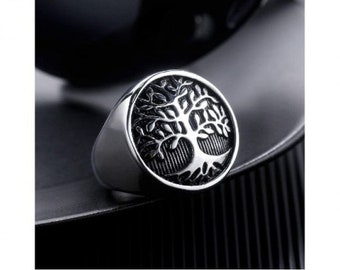 May include: A silver ring with a black tree of life design. The ring is on a black background.