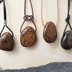 May include: Four brown stone pendants on leather cords. The stones are different shapes and sizes. The cords are tied in different ways.