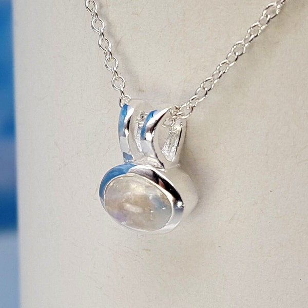 May include: A silver necklace with a moonstone pendant. The pendant is oval shaped and set in a silver bezel.