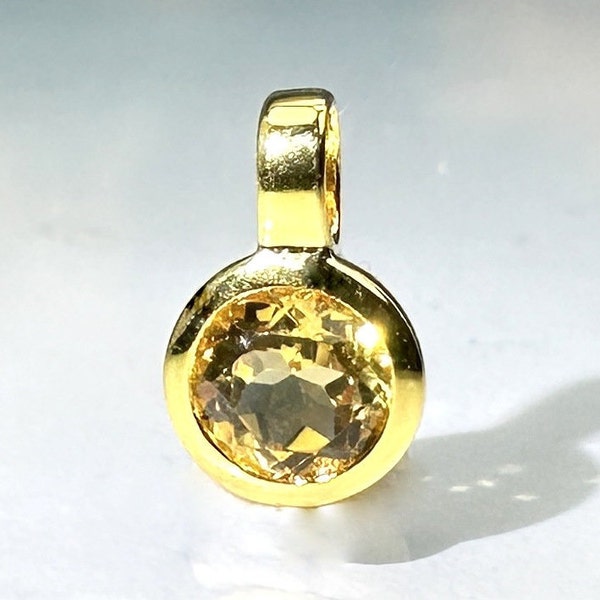 May include: A gold pendant with a round, yellow gemstone.