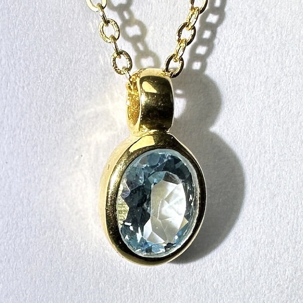 May include: A gold chain necklace with a pendant featuring a light blue oval gemstone.