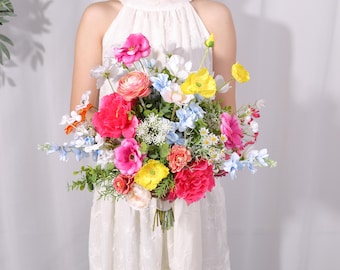 May include: A colorful bridal bouquet with pink, yellow, and blue flowers. The bouquet is made up of various types of flowers, including roses, ranunculus, and daisies.