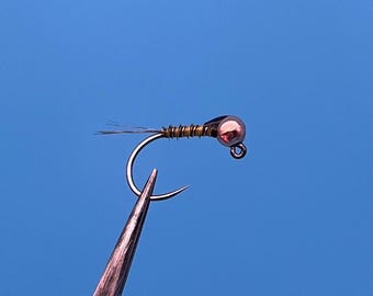 May include: A small, brown and gold fly fishing lure with a copper bead head.