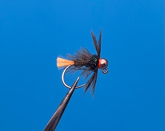 May include: A black and green fly fishing lure with an orange tail and a copper bead head.