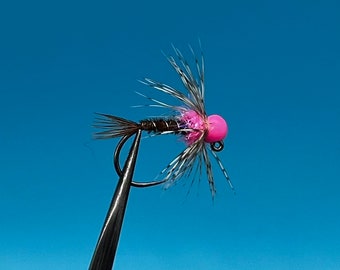 Könnte beinhalten: Eine pinkfarbene Perlen-Fliegenbinde mit schwarzen und weißen Federn.