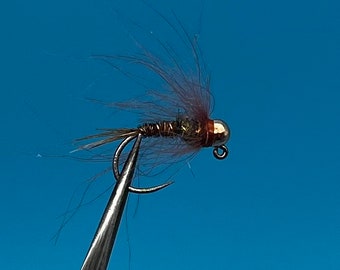 May include: A brown and silver fly fishing lure with a brown feather tail and a gold bead head.