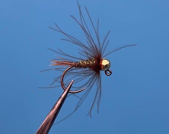 May include: A brown and gold fly fishing lure with a red bead and a gold hook. The lure is tied with brown and gold feathers.