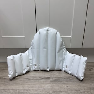 May include: White inflatable back support with multiple chambers. The back support is designed to provide comfort and support for the back.