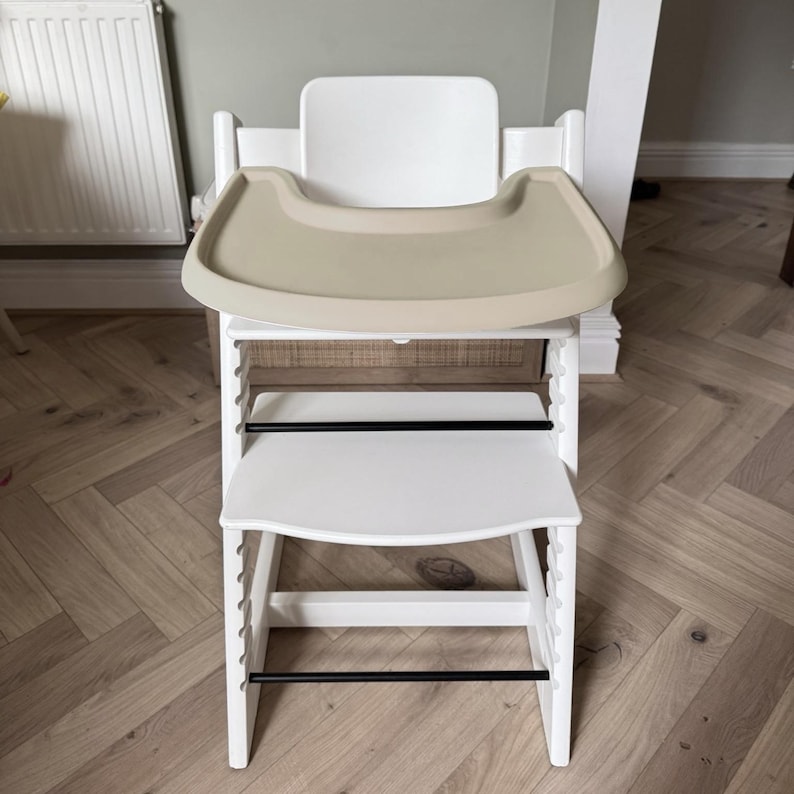 A high chair with a cream full cover silicone place mat on the attached tray.