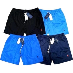 May include: Four pairs of swim trunks in black, light blue, and navy blue. Each pair has a drawstring, a small red logo, and a tag. The trunks are made of a smooth, shiny material.