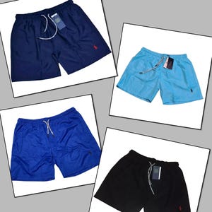 May include: Four pairs of solid-color shorts in navy blue, light blue, royal blue, and black. Each pair features a drawstring waist, a small logo, and a tag. The shorts are displayed on a white background.
