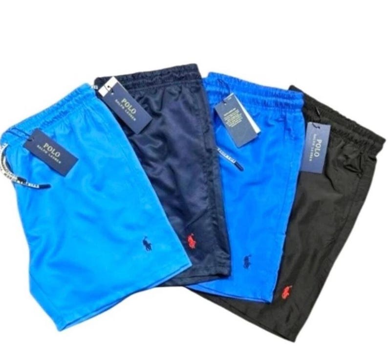 May include: Four pairs of men's swim trunks in various colors: light blue, navy, bright blue, and black. Each pair features a drawstring waist, a small logo, and a tag that reads "POLO".