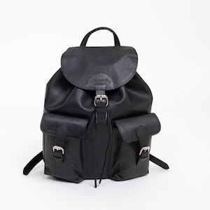 Könnte beinhalten: Ein schwarzer Rucksack mit einem Überschlag und Schnallenverschluss, zwei Vordertaschen mit Schnallenriemen und einem Tragegriff. Der Markenname Redland ist auf dem Überschlag eingeprägt. Die Tasche hat eine glatte Oberfläche und silberne Beschläge.