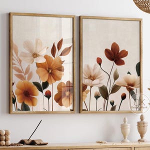 以下が含まれることがあります： オレンジとクリーム色の花が描かれた、額入りのフラワーアートプリント2点。プリントは、織りパネルが付いた木製キャビネットの上に飾られています。部屋は、織り込まれた照明器具と、織り込まれた椅子のあるダイニングテーブルで装飾されています。左上のテキストは「DIGITAL DOWNLOAD OKDesignPark.etsy.com」です。