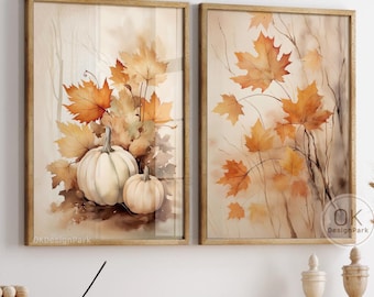 May include: Two watercolor paintings in gold frames. The painting on the left features a still life of white pumpkins with orange and brown fall leaves. The painting on the right features a branch of orange and brown fall leaves.