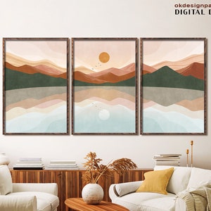 Può includere: Tre stampe digitali di un paesaggio minimalista con montagne, un lago e un sole. Le stampe sono in una tavolozza di colori caldi di marrone, arancione, rosa e blu. Le stampe sono incorniciate in cornici di legno marrone.