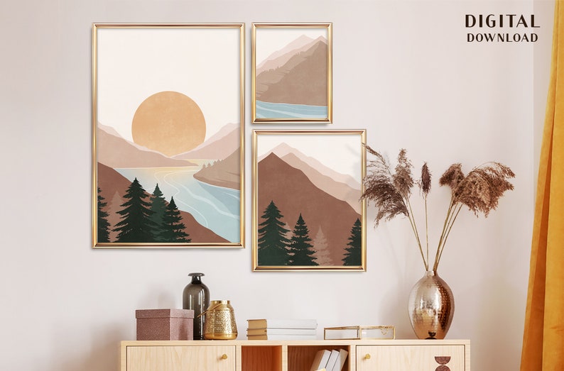 K&ouml;nnte beinhalten: Drei digitale Drucke von abstrakten Landschaften mit Bergen, B&auml;umen und einem See. Die Drucke sind in Gold gerahmt und haben einen minimalistischen Stil.