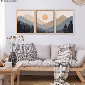 Pode incluir: Tr&ecirc;s impress&otilde;es emolduradas de uma paisagem de montanha minimalista com um sol na impress&atilde;o central. As impress&otilde;es est&atilde;o em uma sala de estar com um sof&aacute;, almofadas e um cobertor.