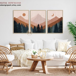 May include: Three digital art prints featuring a minimalist mountain landscape with a forest in the foreground. The prints are in a muted color palette of brown, pink, and blue. The first print features a sun, the second print features a mountain peak, and the third print features a crescent moon.