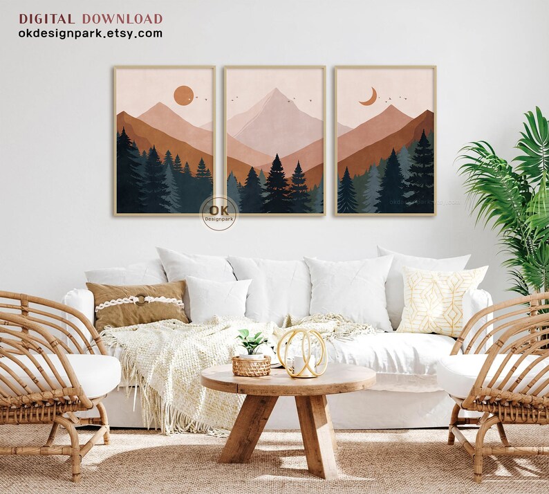 May include: Three digital art prints featuring a minimalist mountain landscape with a forest in the foreground. The prints are in a muted color palette of brown, pink, and blue. The first print features a sun, the second print features a mountain peak, and the third print features a crescent moon.