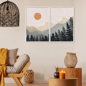 K&ouml;nnte beinhalten: Zwei gerahmte Drucke einer Berglandschaft mit einer Sonne am Himmel und einem Wald aus Kiefern im Vordergrund. Die Drucke sind im minimalistischen Stil mit gedeckten Farben gehalten.