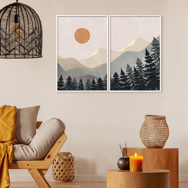 K&ouml;nnte beinhalten: Zwei gerahmte Drucke einer Berglandschaft mit einer Sonne am Himmel und einem Wald aus Kiefern im Vordergrund. Die Drucke sind im minimalistischen Stil mit gedeckten Farben gehalten.