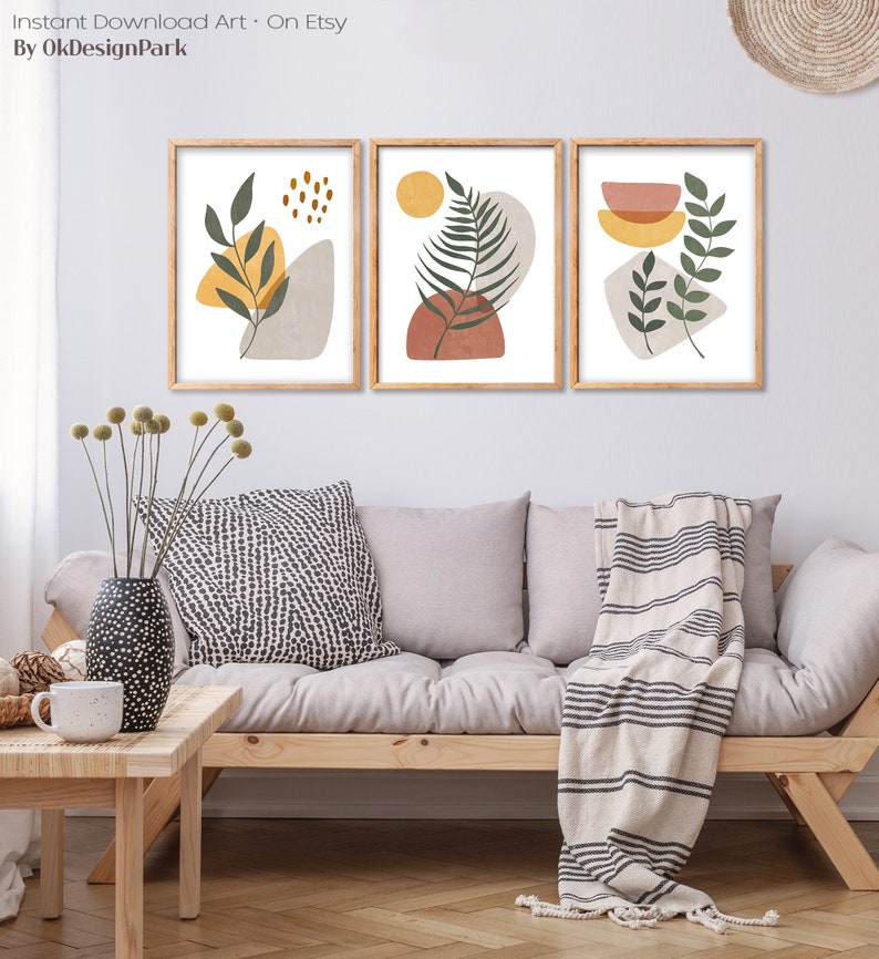 Puede incluir: Tres impresiones de arte abstracto enmarcadas con un dise&ntilde;o minimalista que presenta hojas verdes, formas amarillas y naranjas y un fondo blanco.