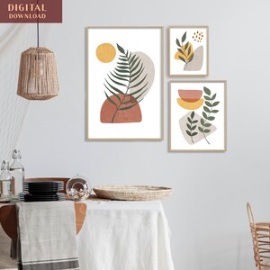 Puede incluir: Tres impresiones de arte abstracto con un estilo minimalista. Las impresiones presentan hojas verdes, formas geom&eacute;tricas marrones y amarillas y un fondo blanco. Las impresiones est&aacute;n enmarcadas en un marco de madera claro.