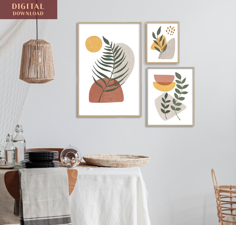 Puede incluir: Tres impresiones de arte abstracto con un estilo minimalista. Las impresiones presentan hojas verdes, formas geom&eacute;tricas marrones y amarillas y un fondo blanco. Las impresiones est&aacute;n enmarcadas en un marco de madera claro.