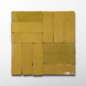 Puede incluir: Disposición cuadrada de baldosas rectangulares esmaltadas en tonos amarillos y verde oliva. Las baldosas están dispuestas en un patrón, con algunas orientadas horizontalmente y otras verticalmente. La superficie brillante refleja la luz.