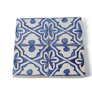 Könnte beinhalten: Vier blaue und weiße Keramikfliesen mit einem geometrischen Muster. Die Fliesen sind quadratisch angeordnet.