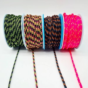 May include: Four spools of colorful braided cord, each with a different color combination. The cords are black with neon green, black with orange and yellow, black with orange and blue, and hot pink with orange. The cords are unraveled and hanging down from the spools.