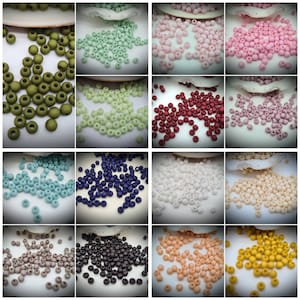 Peut inclure: Assortiment de 12 couleurs de perles rondes à finition mate. Les perles sont disposées en rangées sur une surface blanche. Les couleurs comprennent le vert, le vert clair, le rose, le rouge, le blanc, le bleu clair, le bleu foncé, le marron, le gris, le beige, l'orange et le jaune.