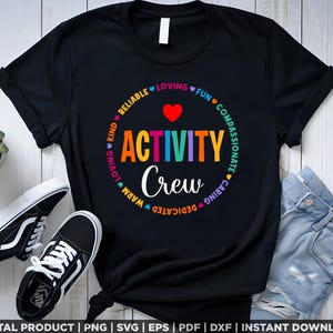 K&ouml;nnte beinhalten: Schwarzes T-Shirt mit einem regenbogenfarbenen Kreis, auf dem "Activity Crew" steht und der von den W&ouml;rtern "Loving, Kind, Reliable, Loving, Fun, Compassionate, Caring, Dedicated, Warm" umgeben ist.