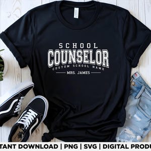 Może przedstawiać: Czarna koszulka z białym napisem "SCHOOL COUNSELOR", z miejscem na niestandardową nazwę szkoły i nazwisko "MRS. JAMES". Koszulka jest prezentowana z czarno-białymi trampkami i niebieskimi dżinsami.