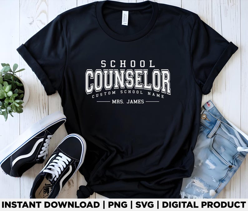 Może przedstawiać: Czarna koszulka z białym napisem "SCHOOL COUNSELOR", z miejscem na niestandardową nazwę szkoły i nazwisko "MRS. JAMES". Koszulka jest prezentowana z czarno-białymi trampkami i niebieskimi dżinsami.