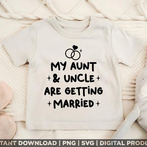 May include: A cream-colored toddler t-shirt with the text "MY AUNT & UNCLE ARE GETTING MARRIED" in black. Above the text are two interlocking rings with a heart. The shirt is on a white textured surface.
