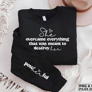 May include: Black sweatshirt with white text that reads "She overcame everything that was meant to destroy her" and "powerful" on the sleeve.