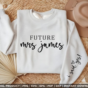 Può includere: Una felpa grigia chiaro con il testo "FUTURE mrs james" in lettere nere sul davanti e "i said yes!" sulla manica.