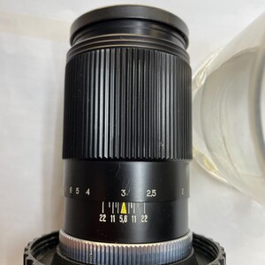 May include: A black camera lens with a silver ring and a black aperture ring with markings for f/22, f/11, f/5.6, f/11, and f/22.