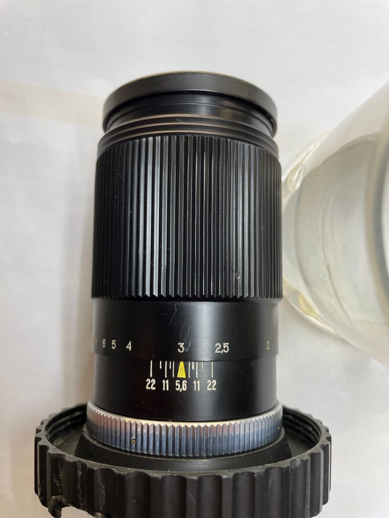 May include: A black camera lens with a silver ring and a black aperture ring with markings for f/22, f/11, f/5.6, f/11, and f/22.