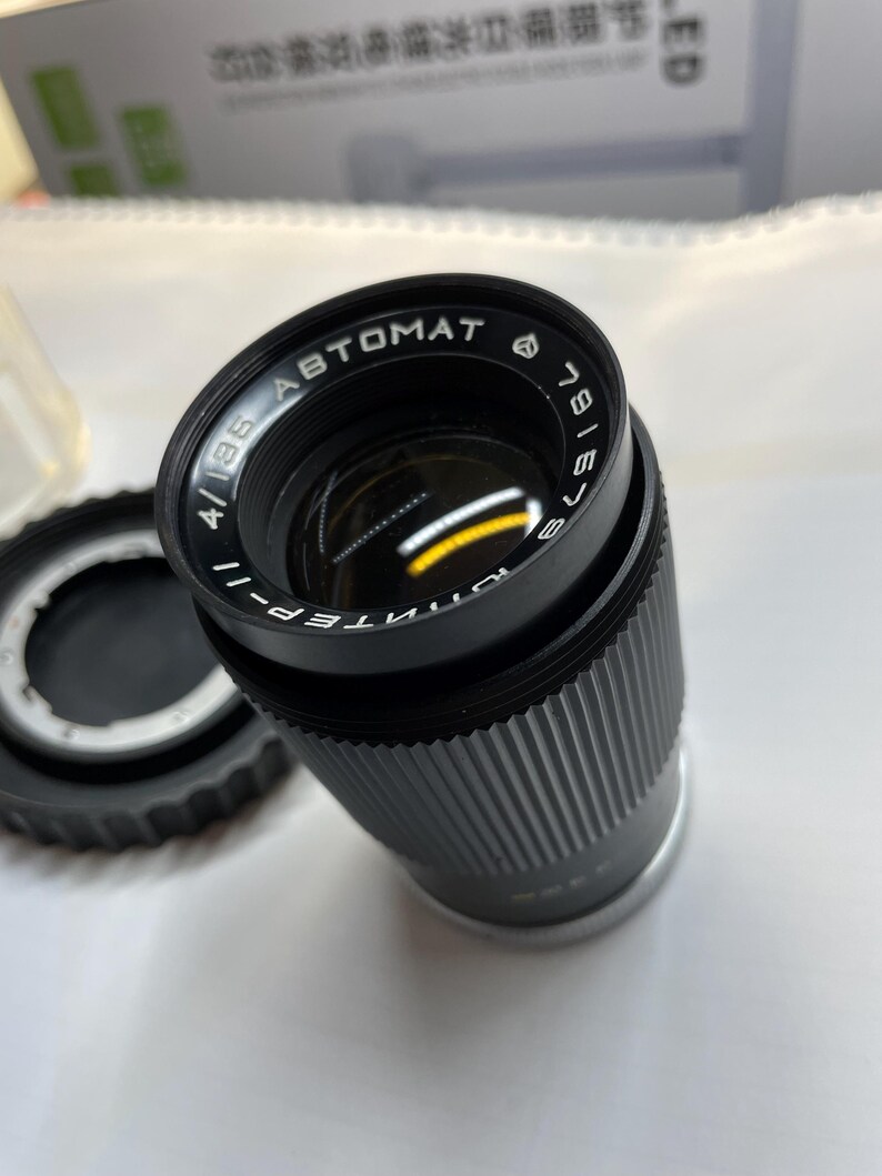 May include: A black camera lens with the text "INTENS-4/135 ABTOMAT 781673" printed on the side.