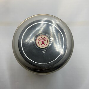 May include: A silver metal container with a black lid and a red and white sticker that says "CCCP" in Cyrillic lettering.