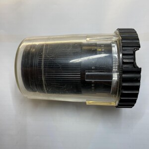 May include: A black camera lens with a clear plastic protective case. The lens has a silver ring with markings that include "50 1.5 30 5 1.5 30 5".