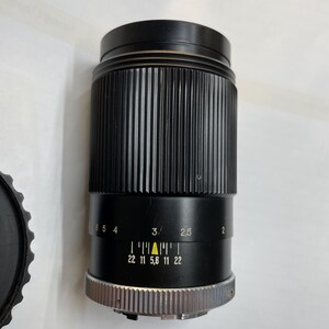 May include: A black camera lens with a silver ring and a yellow triangle marking the aperture setting. The lens has a depth of field scale marked with numbers from 2 to 6 and aperture settings from 22 to 5.6.
