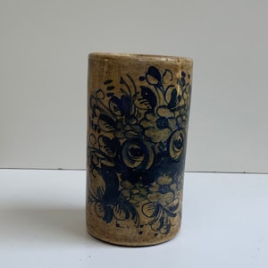 Peut inclure: Un vase en céramique cylindrique avec un motif floral bleu et jaune. Le vase est peint à la main avec un motif floral dans des tons de bleu sur un fond jaune.