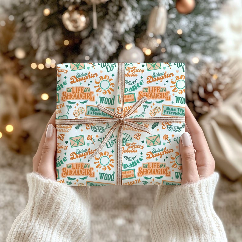 May include: A wrapped gift with a patterned paper featuring text and illustrations in teal, orange, and white. The gift is tied with a brown ribbon and bow. The text includes "The Life of a Showgirl" and "Eldest Daughter".