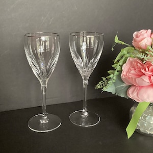 May include: Two clear glass wine glasses with a silver rim. The glasses have a diamond-shaped pattern on the bowl and a long, thin stem.