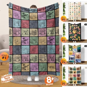 May include: A rectangular fleece blanket featuring a grid pattern of colorful squares, each containing a black line drawing of a drum kit or drumsticks. The blanket displays various drum set configurations and includes the text Vtrek in one square.