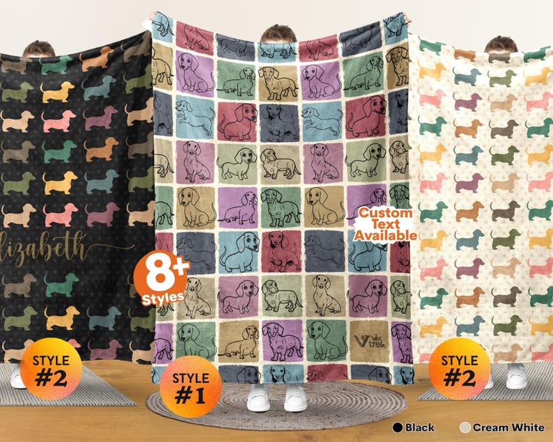 May include: Three soft blankets featuring repeating dachshund patterns. The left blanket is black with colorful dog silhouettes and the name Elizabeth. The center blanket has a grid of colorful squares with dachshund illustrations. The right blanket is cream white.